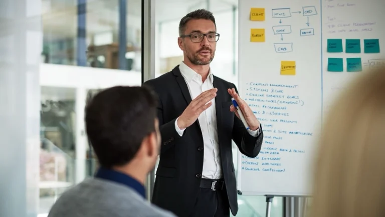 A business expert leading a strategy session on cluster development, discussing market trends and innovation on a whiteboard.