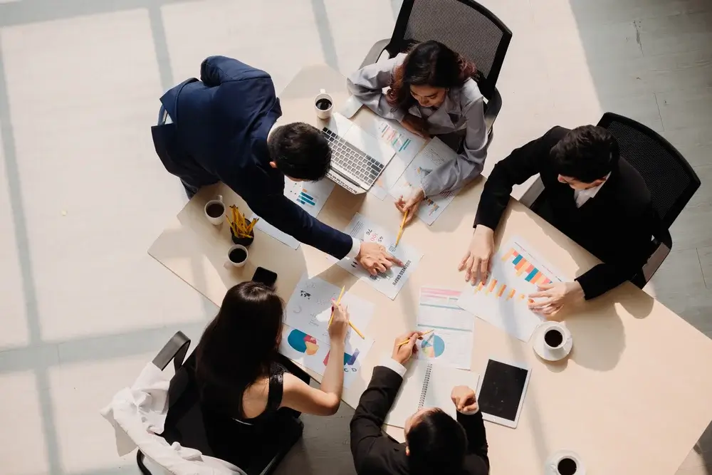 An overhead view of a business team analyzing market research charts and graphs, collaborating on data-driven strategies for business growth.