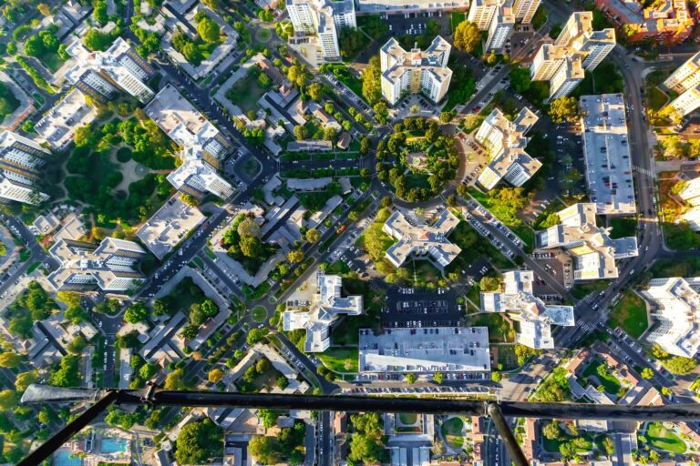 An aerial view of an urban area illustrates cluster development, showing a well-planned city layout with green spaces and modern buildings.