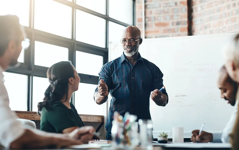 A business expert leading a workshop on proposal development and management services, guiding a team through strategic planning.