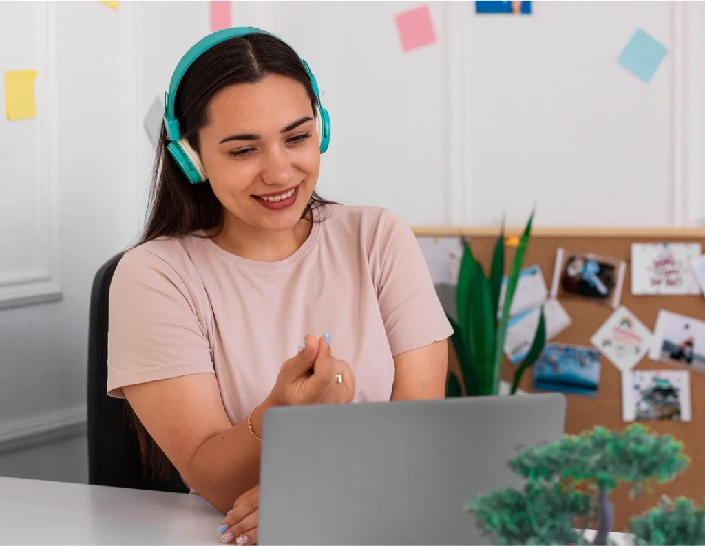 woman sitting at desk with headphones and working on laptop